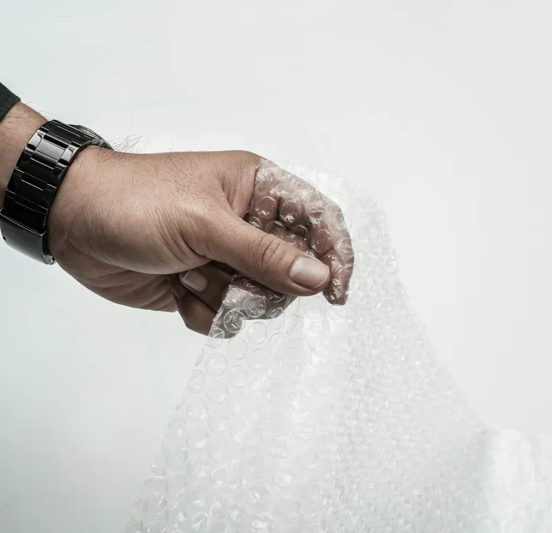 A hand holding a sheet of clear bubble wrap cushioning material