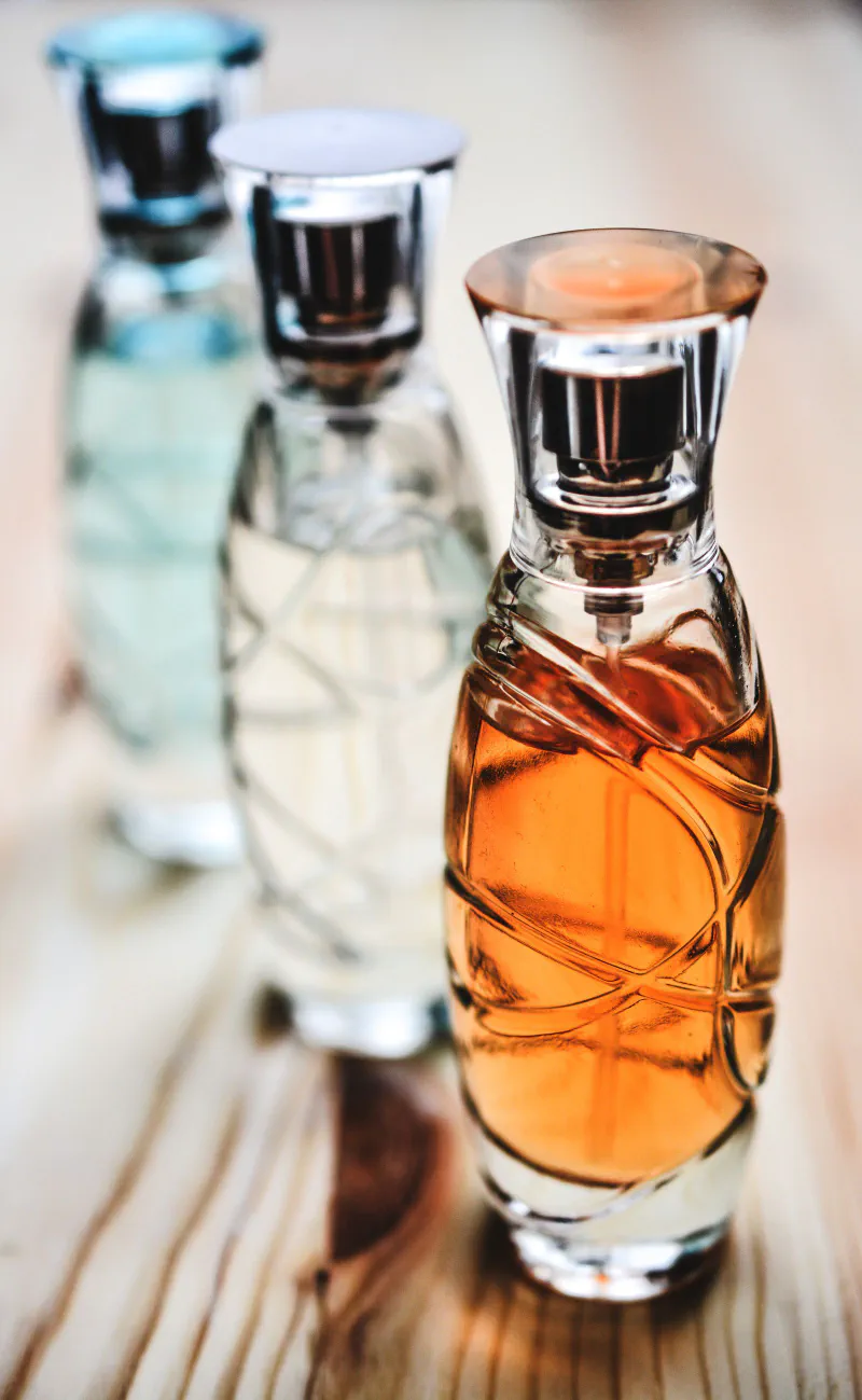 Three glass perfume spray bottles on a wooden table