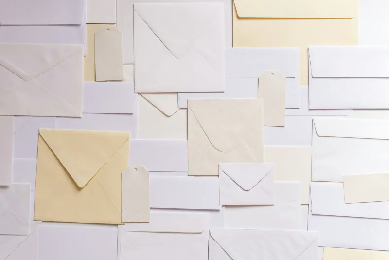 A flat lay of assorted cream and white paper envelopes and gift tags