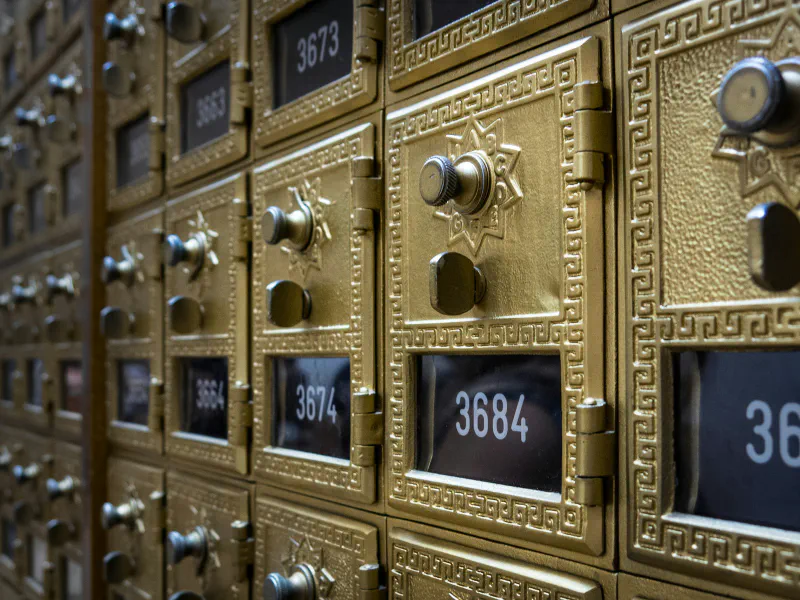 A wall of gold brass post office boxes with numbered doors and combination locks